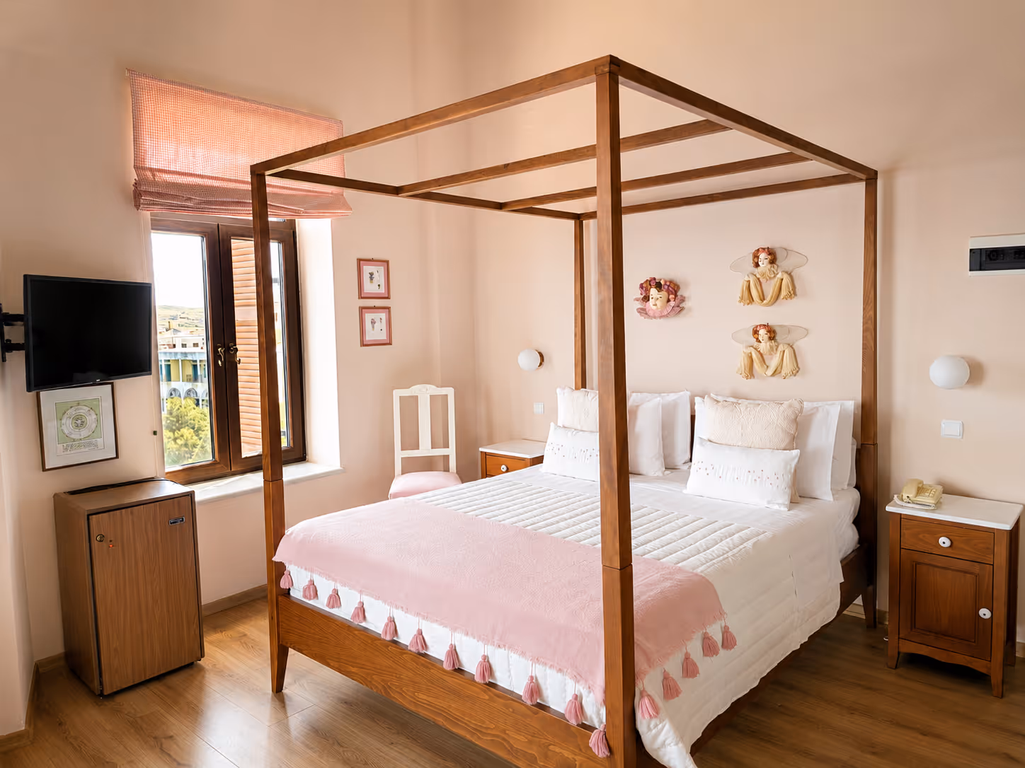 Bedroom with wooden four-poster bed, pink blanket, white pillows, and wall decorations with angels.